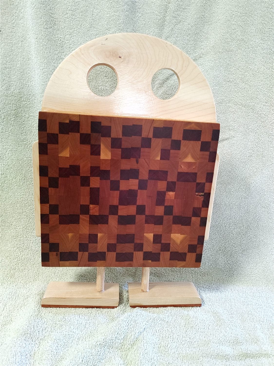 A square end-grain butcher-block cutting board in a checkerboard of light and dark hardwoods.